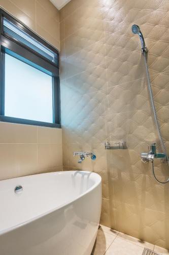 a bathroom with a tub and a shower with a window at The Dawn B&B in Jian