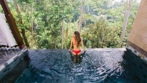 a girl in a swimsuit is in a pool at Tejaprana Resort & Spa - CHSE Certified in Ubud