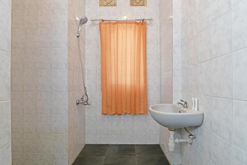 a bathroom with an orange shower curtain and a sink at RedDoorz @ Jalan Gatot Subroto Denpasar in Denpasar