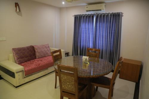 una sala de estar con una mesa y un sofá en Hotel Jyothis Regency, en Palakkad