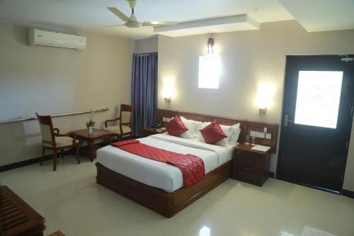 Un dormitorio con una cama grande con almohadas rojas. en Hotel Jyothis Regency, en Palakkad
