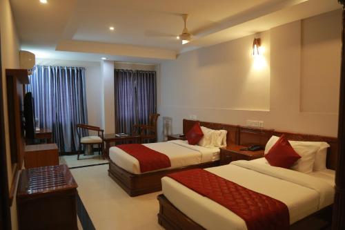 a hotel room with two beds and a table at Hotel Jyothis Regency in Palakkad