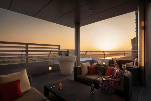 a woman sitting on the balcony of a building at Centro Capital Centre By Rotana in Abu Dhabi