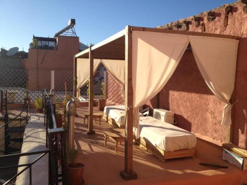 two beds on a deck with a canopy at Riad JEREMY in Marrakech