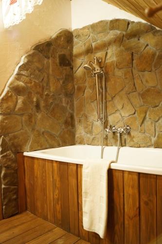 a bathroom with a stone wall and a bath tub at Agroturystyka Smolnikowe Klimaty - Sauna&Jacuzzi in Smolnik