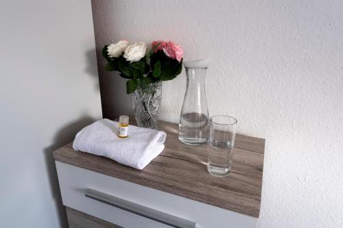 un estante con un jarrón y dos vasos y flores en Hotel Stern en Stuttgart