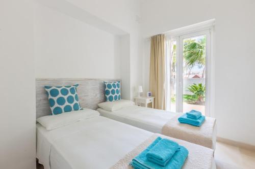 a white bedroom with two beds and a window at Villa Ferreri in Specchiolla 