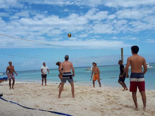 a group of men playing volley ball on the beach at Pearle Beach Resort & Spa in Flic-en-Flac