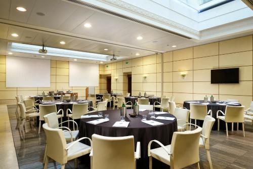 a conference room with tables and chairs and a screen at UNA Hotels Decò Roma in Rome