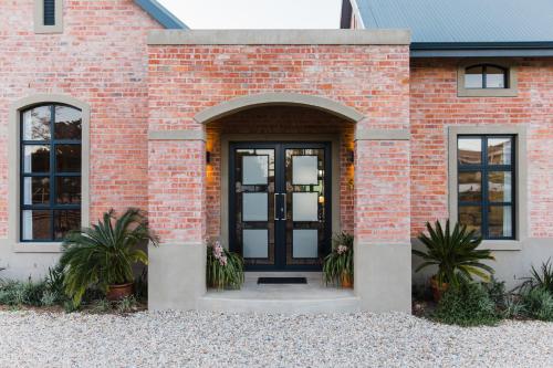 a brick house with a black door and windows at Vineyard Views Country House in Riebeek-Kasteel