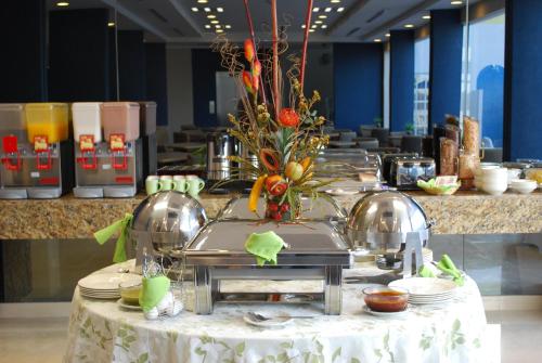 a table with plates and a vase of flowers on it at Rio Vista Inn Business High Class Hotel Poza Rica in Poza Rica de Hidalgo