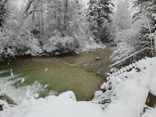 a river with snow on the ground next to a fence at Ferienhaus Pepi in Strobl