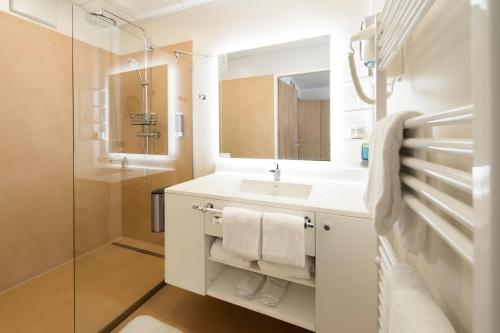 ein weißes Bad mit einem Waschbecken und einer Dusche in der Unterkunft NOVAPARK Flugzeughotel Graz in Graz