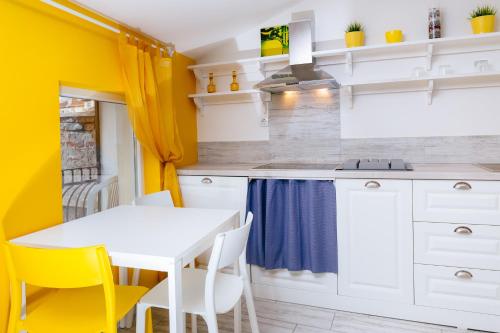 a kitchen with yellow walls and a white table and chairs at Beautiful best location apartment "Blue Mouse" in Plovdiv