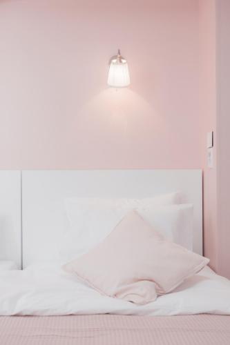 a white bed with a light on the wall at MJ Stay 2 in Seoul