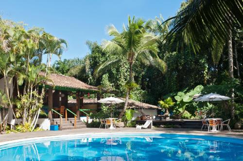 a pool at a resort with tables and umbrellas at Hotel Aldeia de Sahy in Barra do Sahy