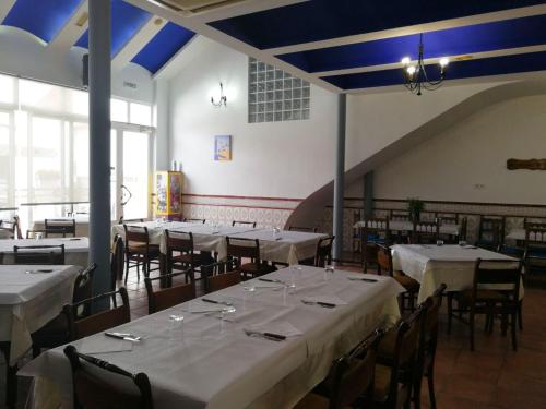 a dining room with tables and chairs with white tablecloths at Hostal Restaurante Ego's in Campo de Criptana