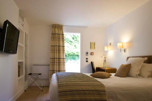 a bedroom with a large bed and a window at Logis Hôtel - Le Manoir de Sauvegrain in Saint-Lambert