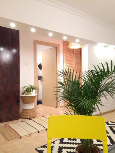 a yellow chair in a lobby with plants at My Little Studio in Bucharest