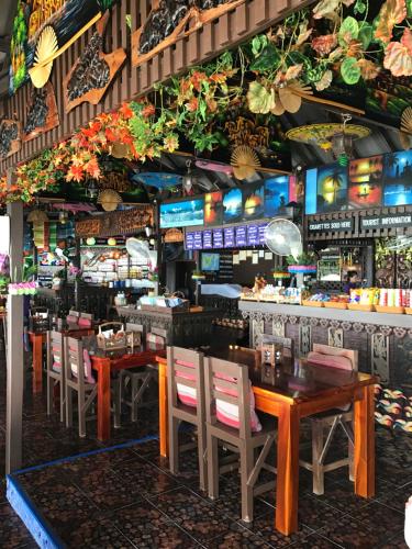 ラマイにあるニュー ハット バンガローのテーブルと椅子のあるレストラン、バー