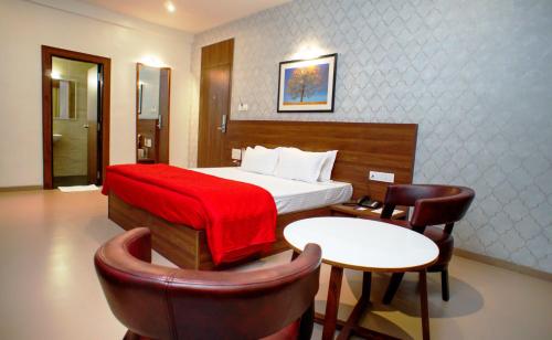 a hotel room with a bed and a table and chairs at Mastiff Hotel Chinchwad by OTHPL in Pune