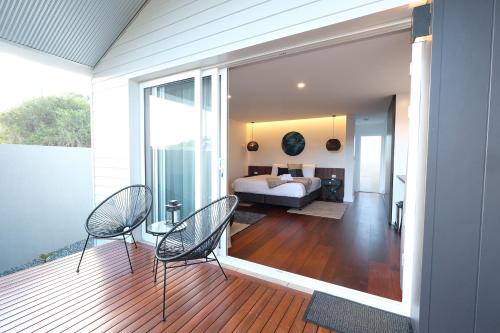 a bedroom with a bed and two chairs on a deck at Jaspers Cabins in Pemberton