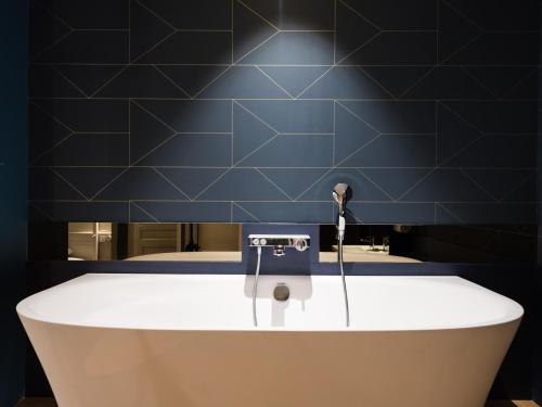 a bath tub in a bathroom with a blue wall at MiHotel Bizolon in Lyon