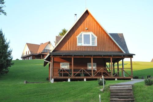 a large wooden house on a green field at Country Houses Vidų Sodyba in Utena