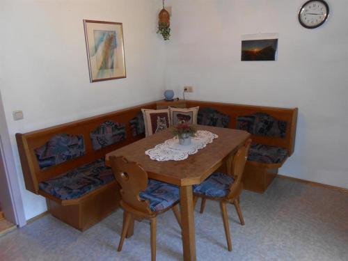 a dining room table with two chairs and a clock at Haus Heiserer in Musau