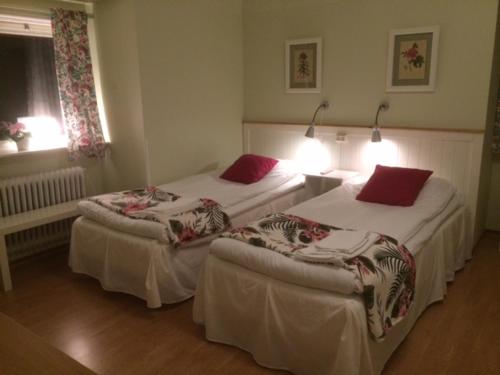 two beds in a hotel room with red pillows at Hotell Paradis in Eksjö