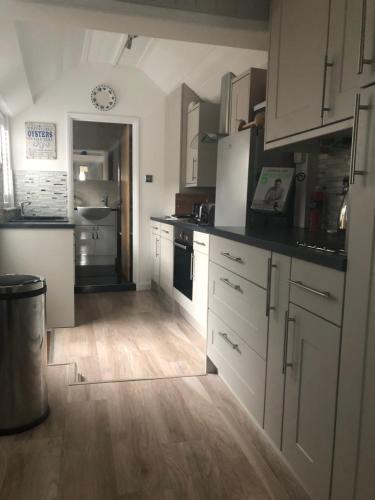 a kitchen with white cabinets and a wooden floor at Marine Cottage in Whitstable