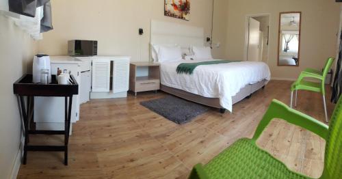 a bedroom with a bed and a desk and a chair at Beverly Corner Lodge in Matatiele