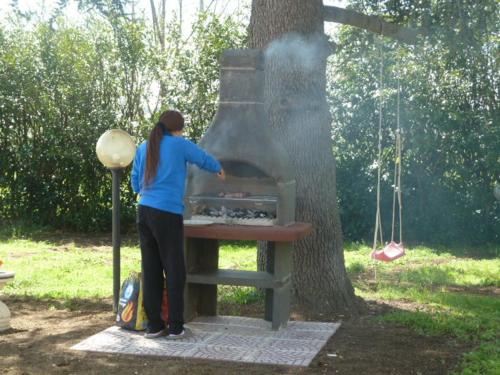 a woman standing next to an outdoor oven in a tree at Il CASALE NELLA TUSCIA. BIOFARM. Casa nel Giardino in Viterbo