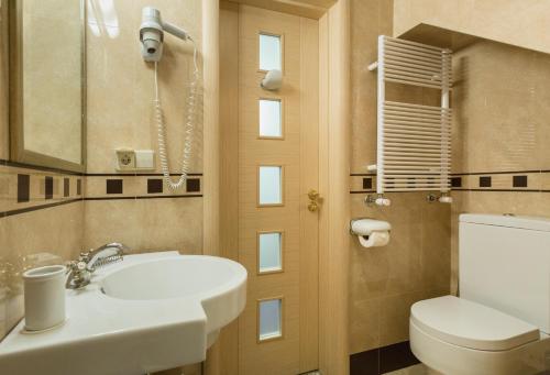 a bathroom with a toilet, sink and mirror at Vinotel Boutique Hotel in Tbilisi City