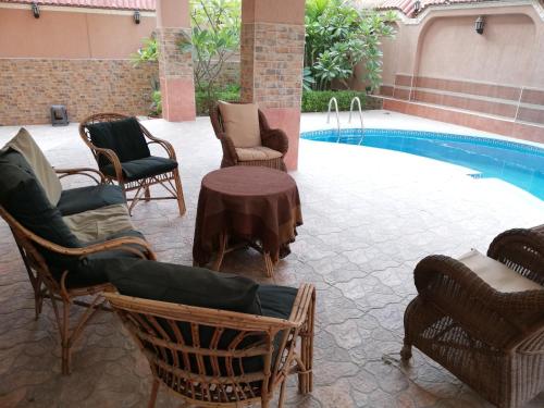 a patio with chairs and a table next to a pool at Magic Studio Pool View, New Cairo in Cairo