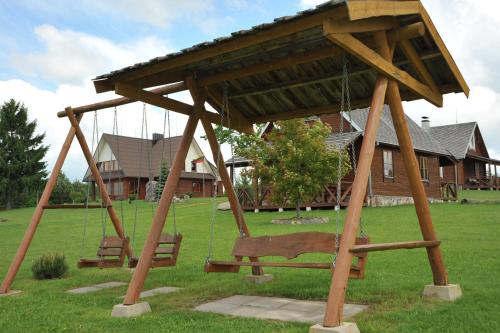 two swings in a park with a house at Country Houses Vidų Sodyba in Utena