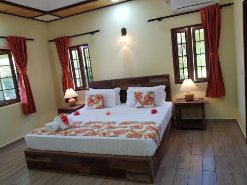 a bedroom with a large bed and two windows at La Passe Holiday Villa in La Digue