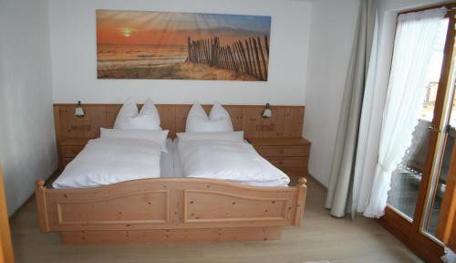 a bedroom with a wooden bed with white pillows at Gästehaus Sonnenbichl in Reit im Winkl