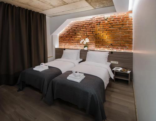 two beds in a room with a brick wall at Dangė Hotel in Klaipėda