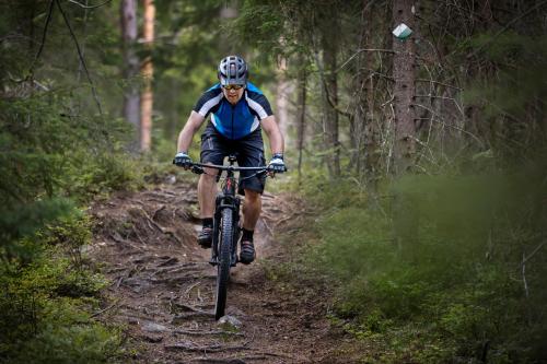 a man riding a bike on a trail in the woods at First Camp Ånnaboda-Örebro in Garphyttan