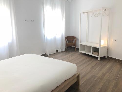 een slaapkamer met een wit bed en een stoel bij Apartamentos La Gloria in Benidorm