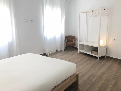 a bedroom with a white bed and a chair at Apartamentos La Gloria in Benidorm