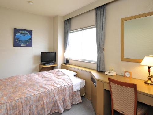 a hotel room with a bed and a desk and a window at Business Hotel Prince in Takamatsu
