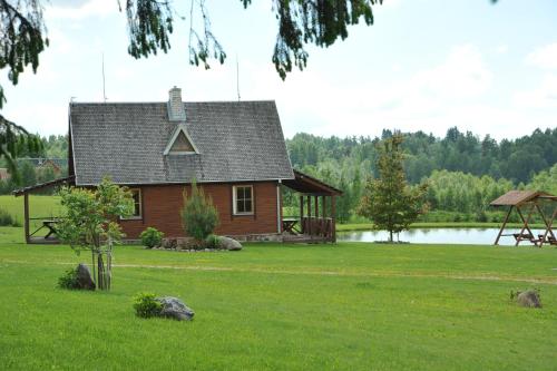 a house on a lawn with a lake in the background at Country Houses Vidų Sodyba in Utena