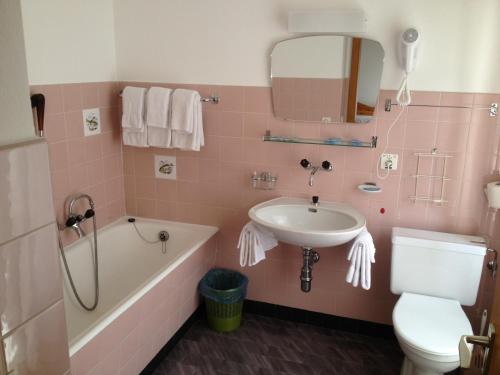 een roze badkamer met een wastafel, een bad en een toilet bij Hotel Des Alpes - Restaurant & Pizzeria in Airolo