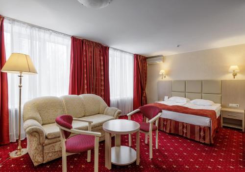 a hotel room with a bed and a table and chairs at AMAKS Park Hotel in Voronezh