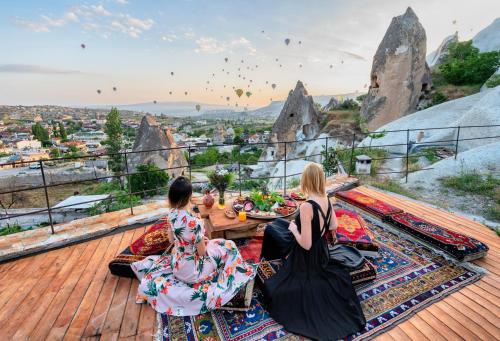 two women sitting on a deck watching hot air balloons at Anatolian Houses Cave Hotel & SPA in Göreme