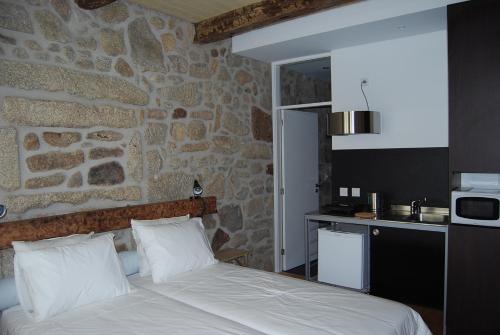 1 dormitorio con cama y pared de piedra en Casa Dos Caldeireiros en Oporto