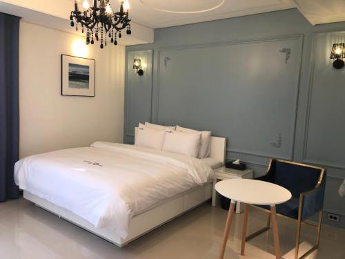 JeongeupにあるRoyal Hotel Jeongeupのベッドとテーブルとシャンデリアのある寝室