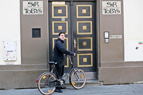 a man on a bicycle in front of a building at Sir Toby's Hostel in Prague